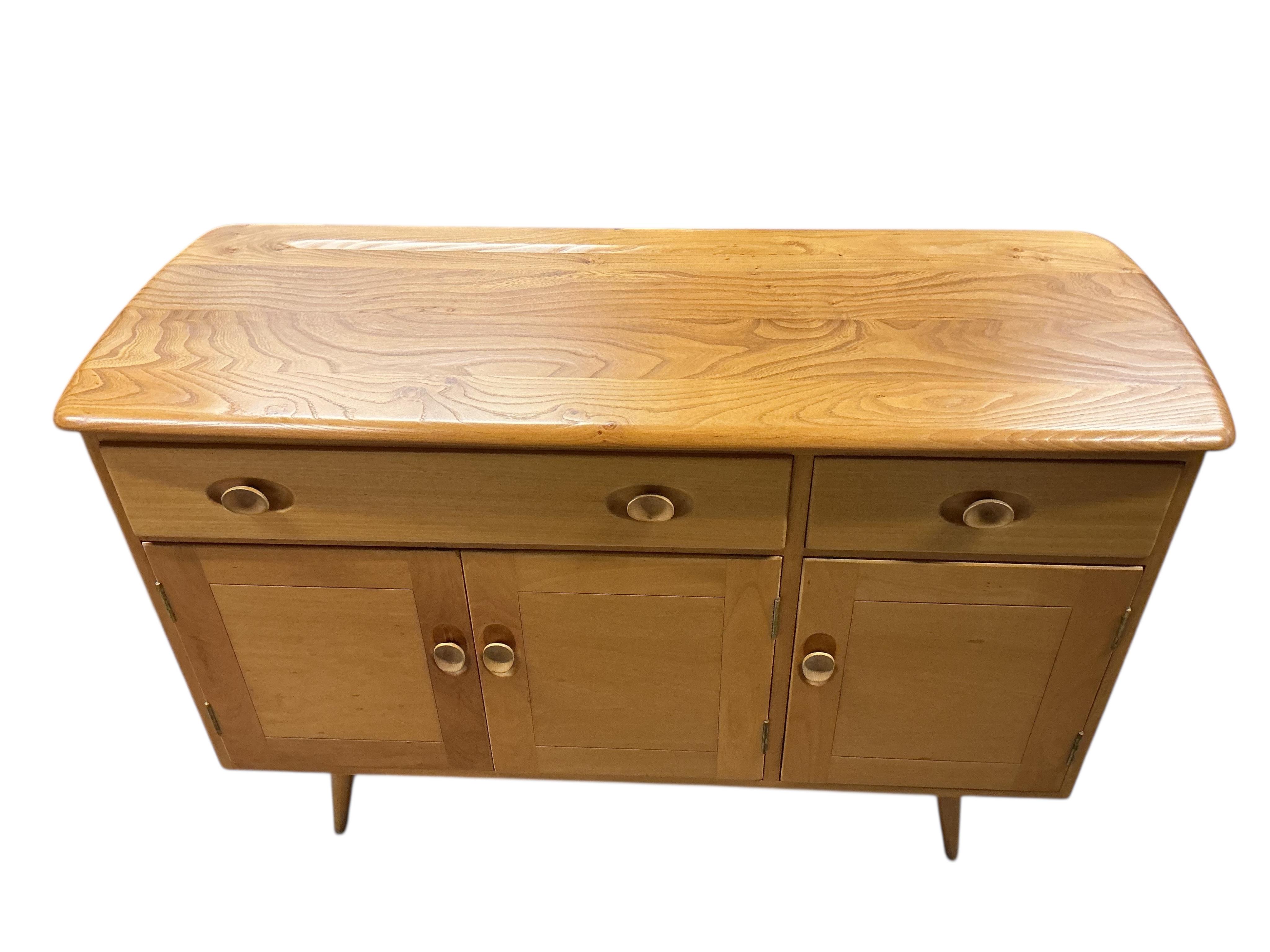 An Ercol elm and beech rectangular dining table, width 150cm, 75cm, height 72cm, together with a set of six Ercol elm and beech comb back dining chairs, two with arms and an Ercol style sideboard